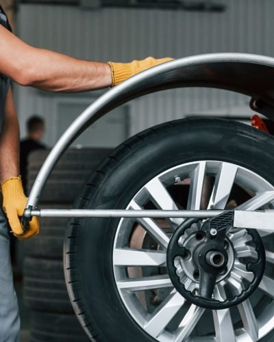 Fixing the tire. Man in uniform is working in the auto service.