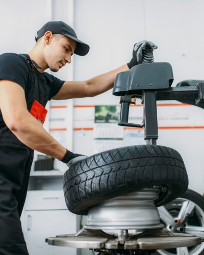 Mechanic change tire, repairing service. Man repairs car tyre in garage, professional automobile inspection in workshop